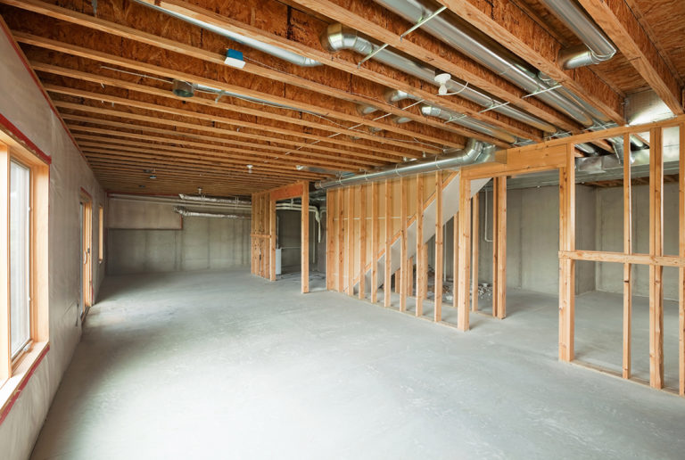 "An unfinished walk-out basement in a large two-story or ranch house. Basements are often left looking like this after initial construction, a cost saving move which allows for future expansion. This image would make a good starting point for a remodeling or house completion concept. The floor and right exterior wall are poured concrete, the left wall is framed, insulated and covered with plastic. The floor joists are engineered I-beams. Some broken concrete is visible behind the far wood frame wall."